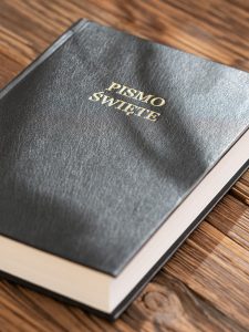 Close-up of a Polish Bible on a wooden surface, emphasizing texture and detail.
